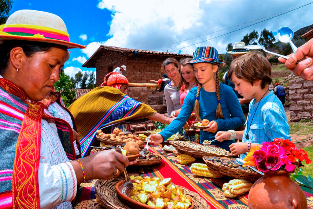 Turistas compartiendo un almuerzo tradicional con familias andinas en un entorno rural, participando en una experiencia cultural auténtica en los Andes Peruanos