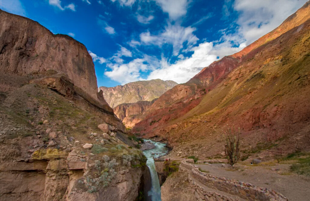 Cataratas de Sipia en el Cañón de Cotahuasi, con agua cayendo entre formaciones rocosas y montañas de colores intensos