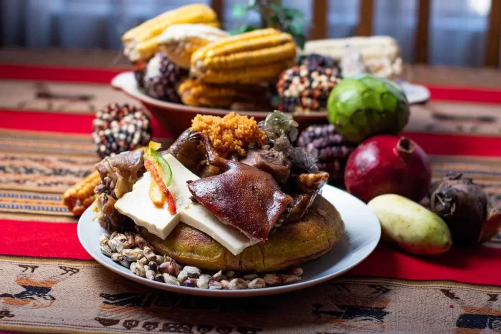Plato de chiriuchu servido con cuy, queso, torreja, maíz tostado y frutas andinas sobre una mesa decorada con textiles tradicionales