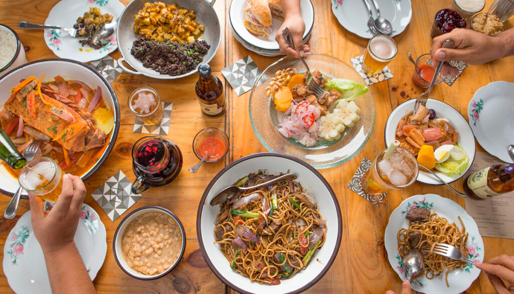 Mesa compartida con platos peruanos típicos y bebidas, representando la diversidad culinaria popular en Lima
