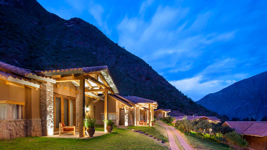 Bungalows de Inkaterra Hacienda Urubamba al atardecer, rodeados de montañas y naturaleza andina