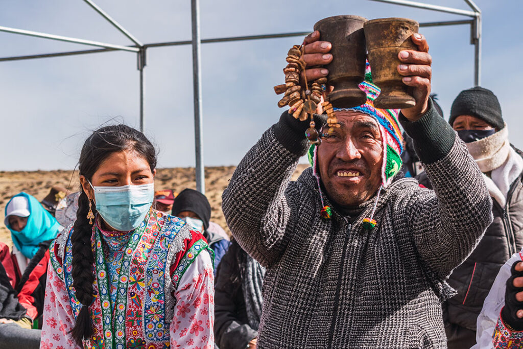 Comunero andino levanta ofrendas a la Pachamama durante la preparación del Chaccu de vicuñas, acompañado por miembros de la comunidad en la sierra peruana