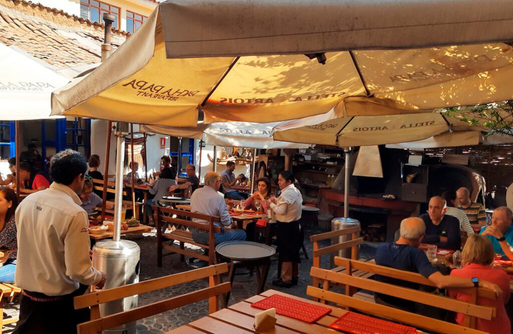 Ambiente al aire libre en el restaurante Pachapapa de Cusco, con comensales disfrutando de la gastronomía local bajo sombrillas tradicionales