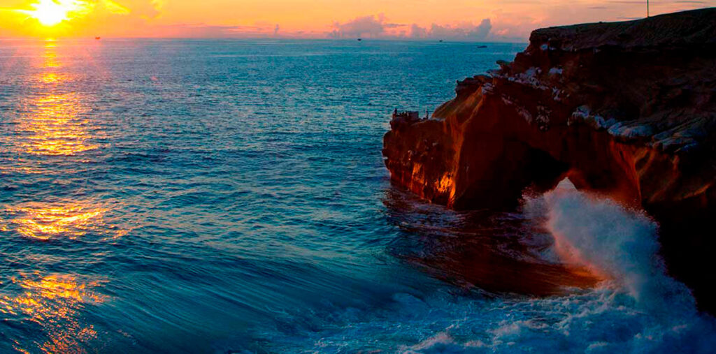 Atardecer sobre el mar de El Ñuro, con formaciones rocosas y aguas tranquilas en la costa de Piura