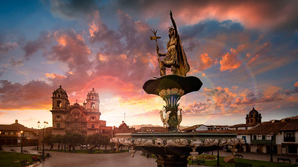 Fuente de la Plaza de Armas del Cusco con la Catedral al fondo durante el atardecer