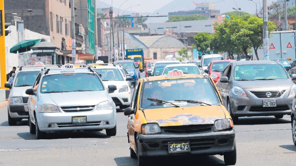 Taxis informales y vehículos deteriorados circulando en una avenida congestionada de Lima, reflejando el desorden del transporte urbano