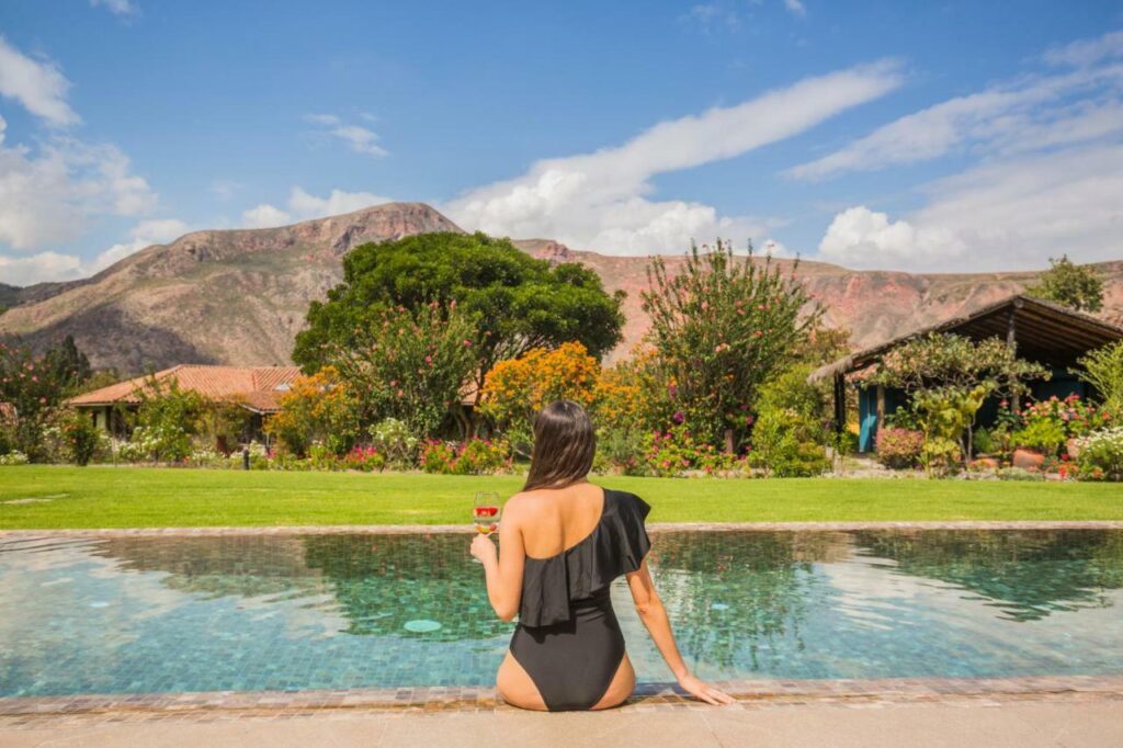 Mujer descansando en la piscina de un hotel en Urubamba, rodeada de jardines y montañas del Valle Sagrado del Cusco