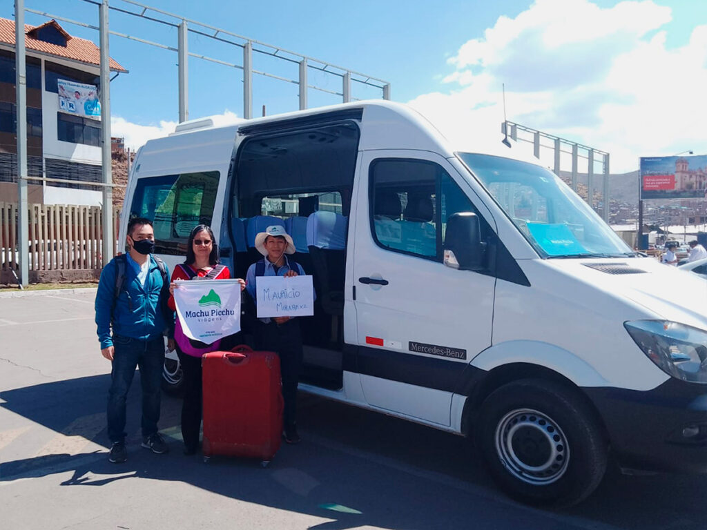 Turistas recibidos por transfer de Viagens Machu Picchu junto a una van privada en zona urbana, listos para iniciar su recorrido