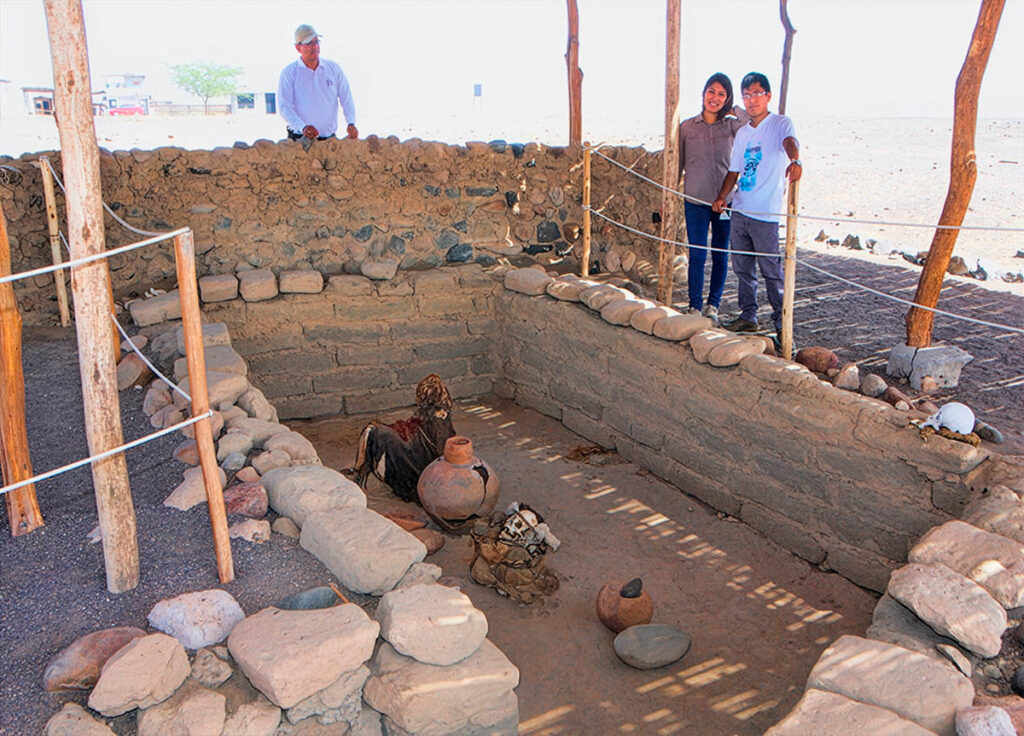 Turistas observando una tumba restaurada en el cementerio de Chauchilla, donde se exhiben momias y vasijas nazca bajo un área protegida