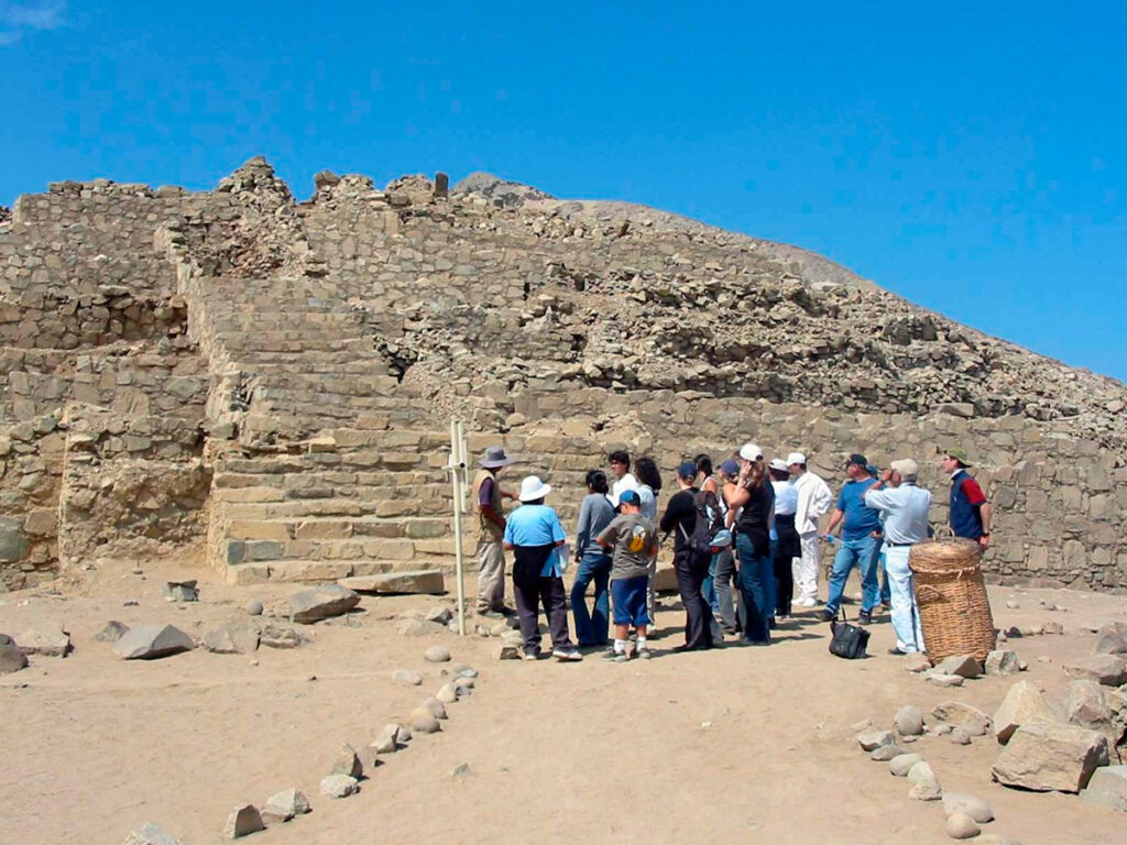 Grupo de visitantes recorriendo las pirámides de piedra en la Ciudad Sagrada de Caral, patrimonio arqueológico y cuna de la civilización andina en el valle de Supe