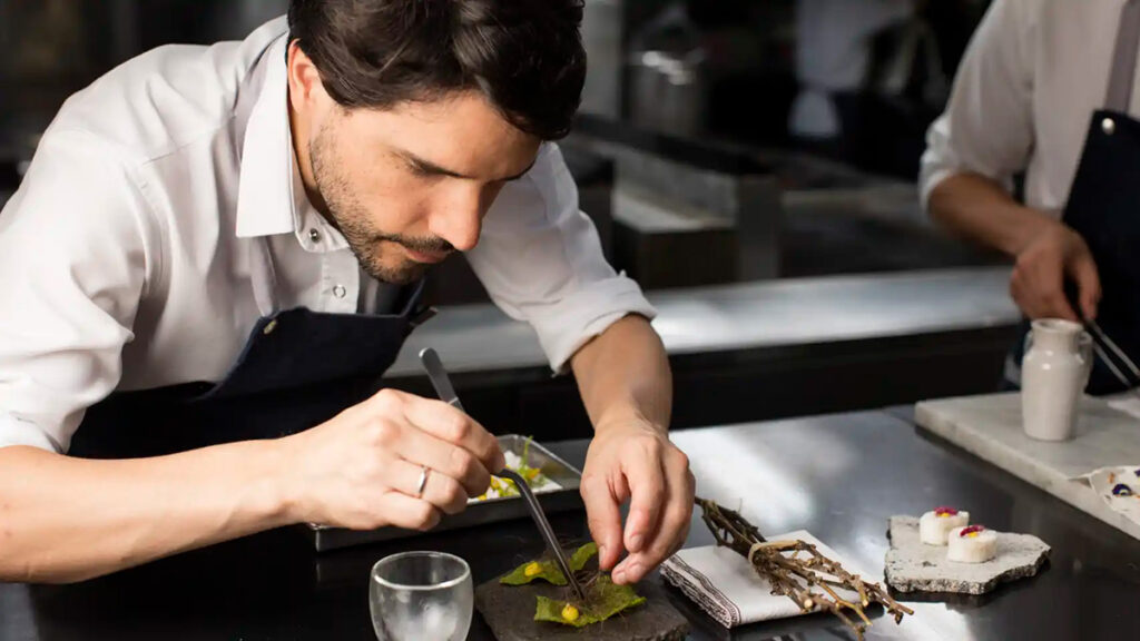 Virgilio Martínez en la cocina de Central, concentrado en el emplatado de un plato de alta cocina inspirado en ecosistemas peruanos