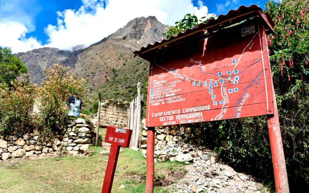 Panel informativo del campamento de Huayllabamba en el Camino Inca, con montañas al fondo y cielo despejado