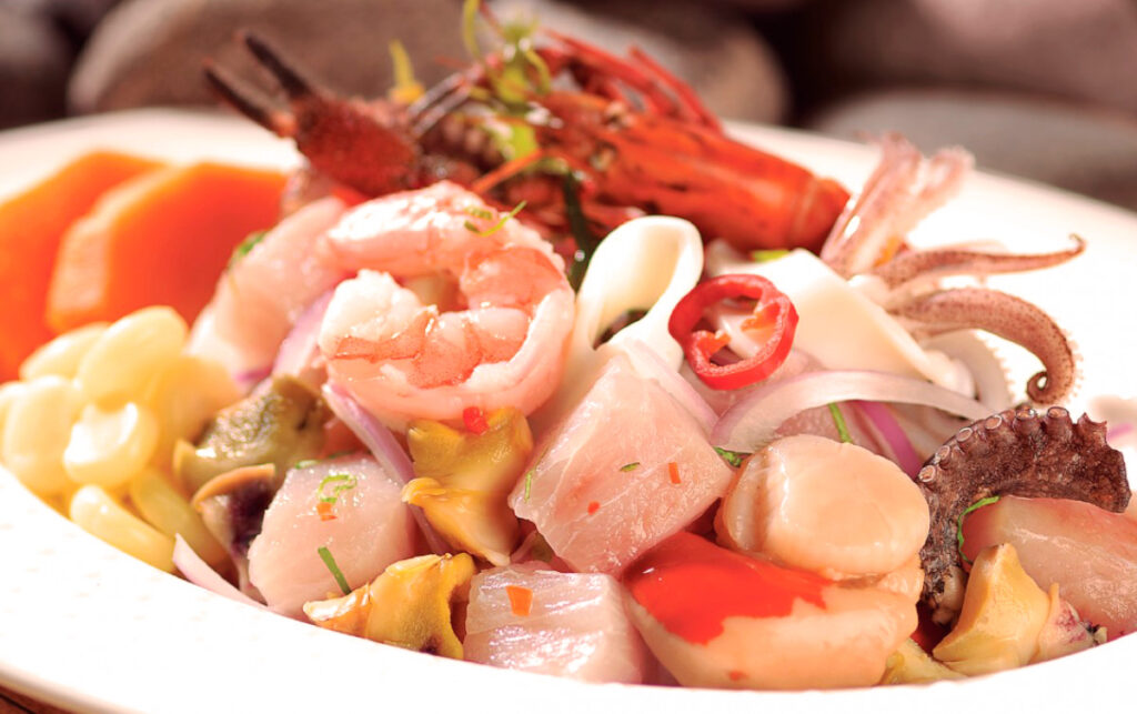 Ceviche mixto con pescado, mariscos, pulpo, langostinos y ají en plato blanco