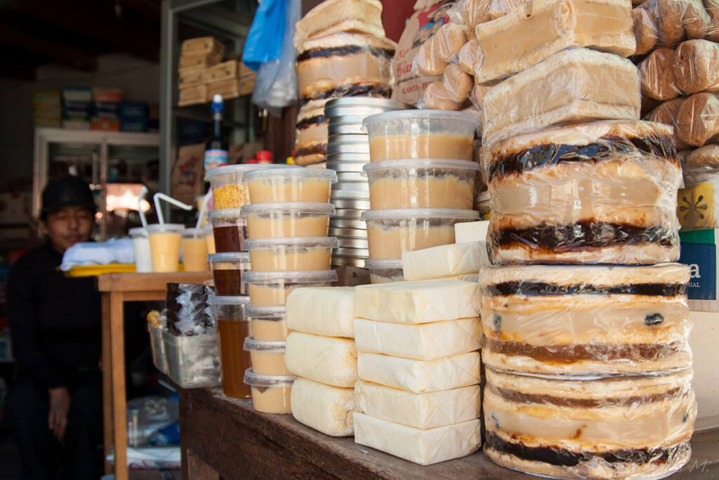 Venta de productos tradicionales en Canta, incluyendo quesos frescos, manjar blanco y dulces artesanales apilados en un puesto local
