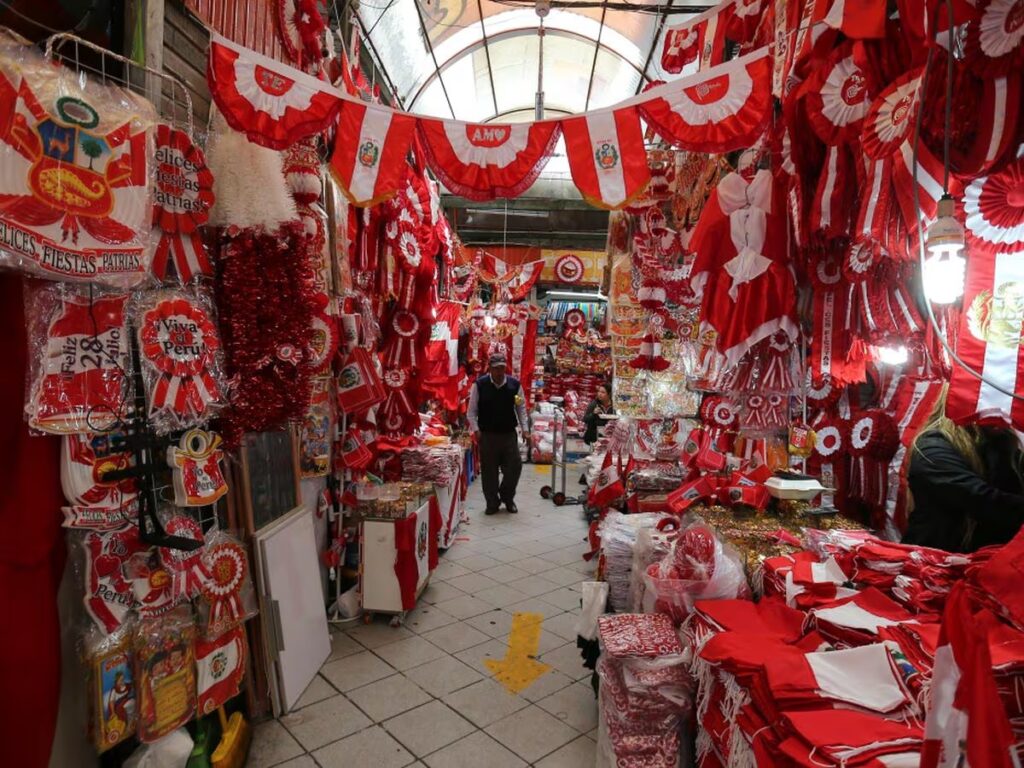 Puestos de venta con adornos rojos y blancos en un mercado limeño por Fiestas Patrias