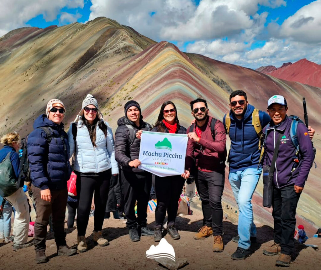 Grupo de turistas con guía turístico de Viagens Machu Picchu durante la visita a la Montaña de 7 Colores, mostrando el paisaje multicolor característico de la cordillera andina