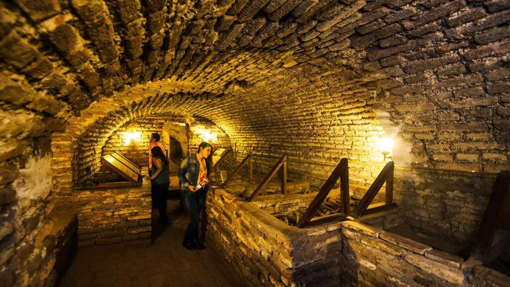 interior de las catacumbas de san francisco en lima con visitantes y osarios iluminados