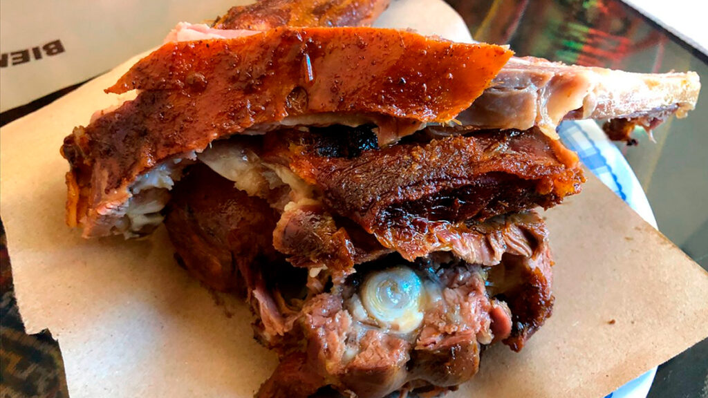 Porción de cancacho ayavireño con piel crocante y carne jugosa, servido sobre papel manteca