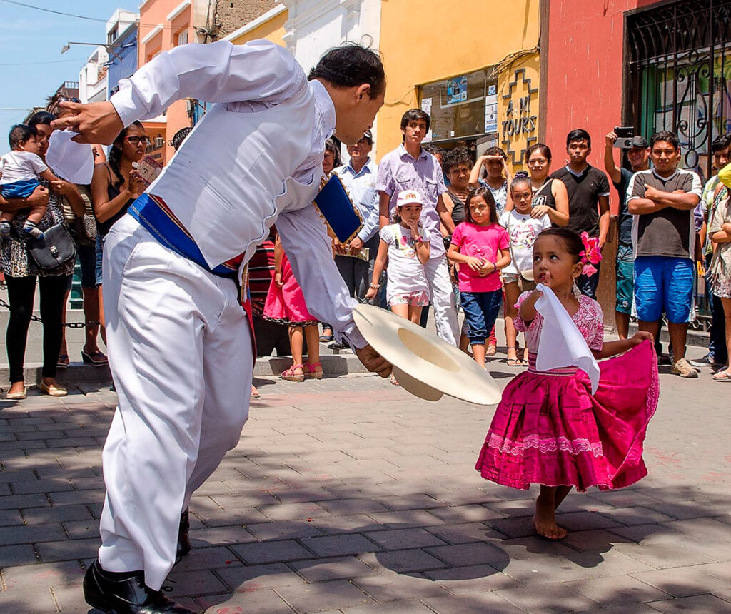Hombre y niña bailando marinera norteña en Monsefú, mostrando el vínculo generacional de las tradiciones costumbristas