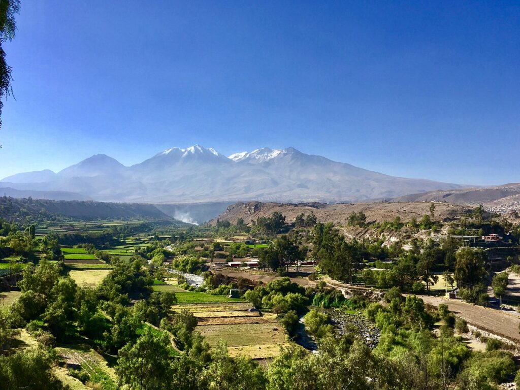 Vista panorámica desde el Mirador de Carmen Alto mostrando la campiña verde de Arequipa y los volcanes Misti, Chachani y Pichu Pichu al fondo