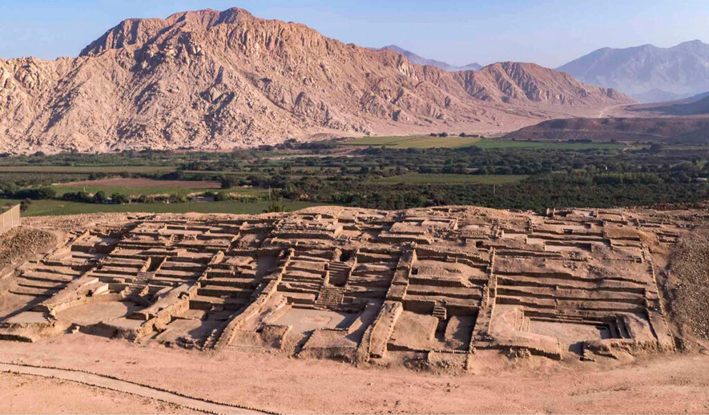 Vista panorámica de las estructuras excavadas en el sitio arqueológico de Peñico, en el valle del Supe, con el paisaje montañoso de fondo