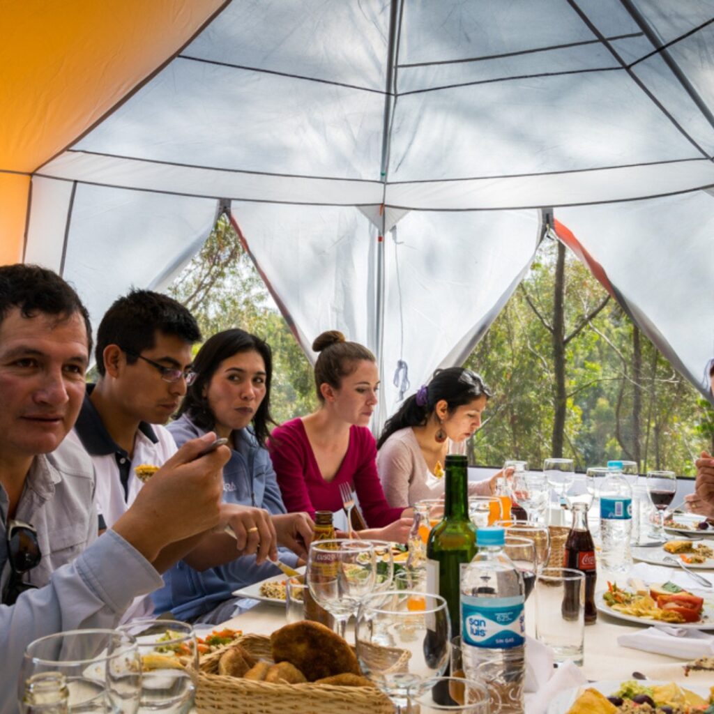  Personas compartiendo un picnic bajo una carpa en un entorno natural cerca de Sacsayhuamán