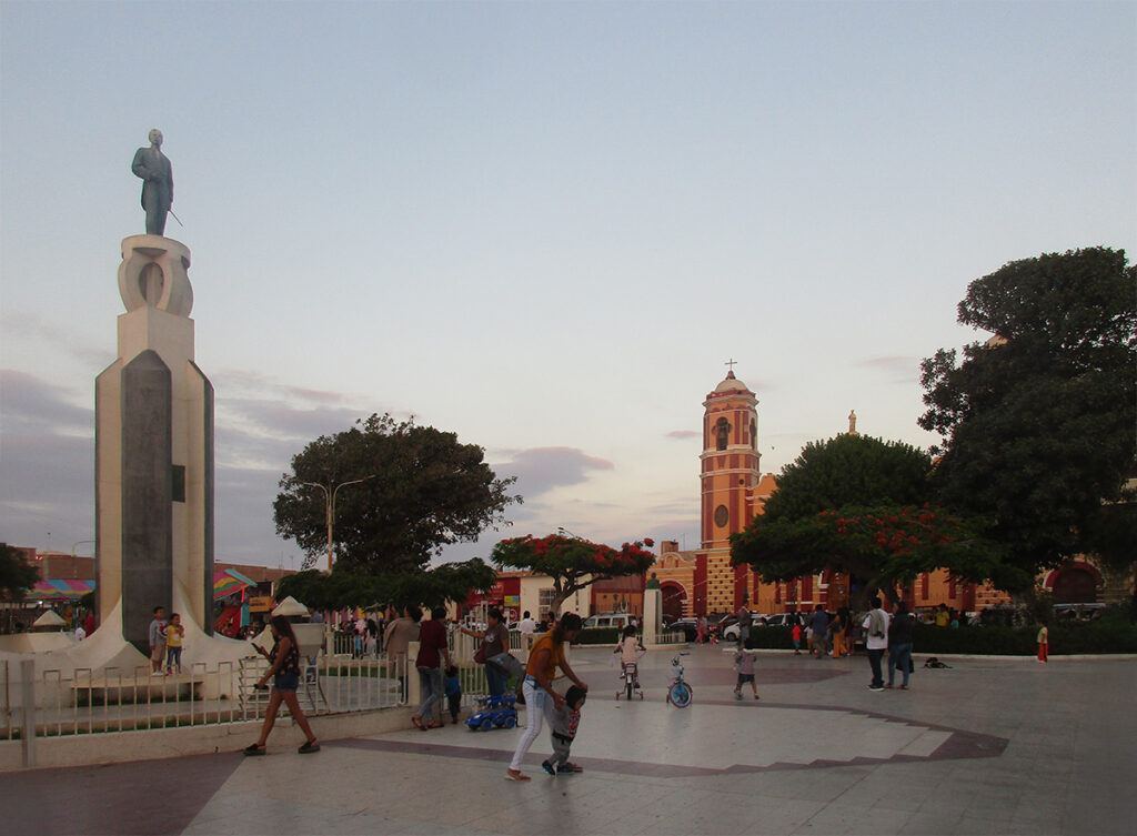 Plaza principal de Monsefú, con monumento y la iglesia de San Pedro al fondo, durante una tarde típica en la región Lambayeque