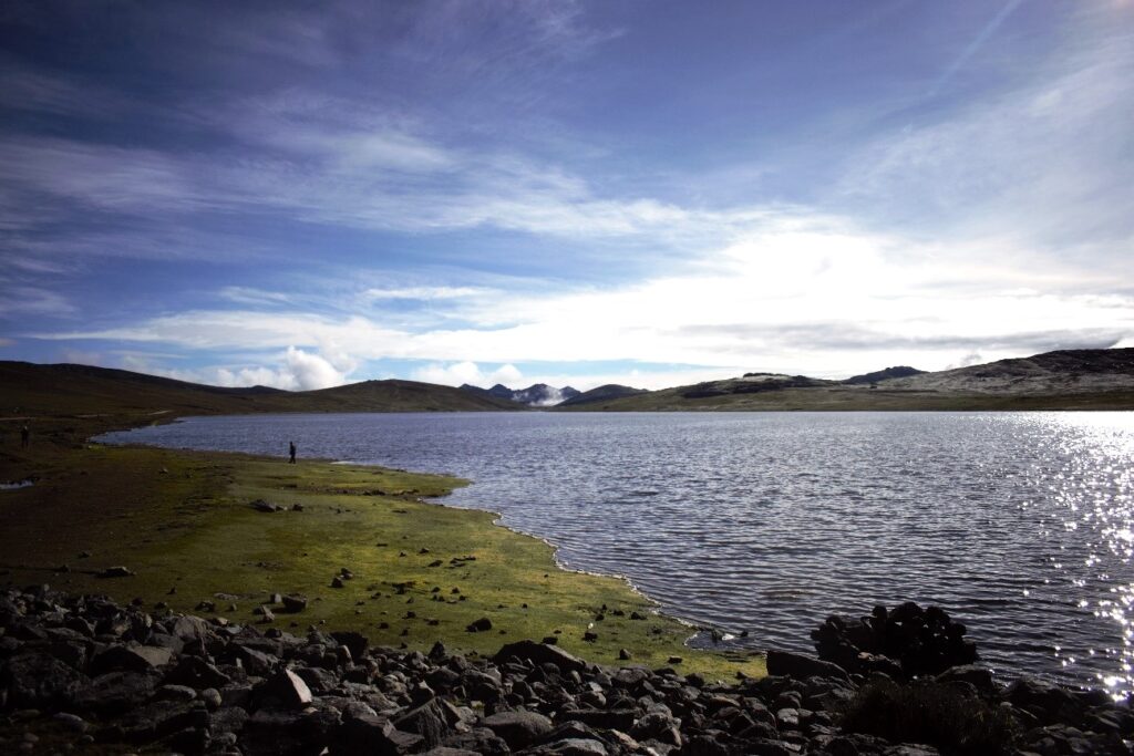 Senderos naturales junto a la Laguna Pomacocha con reflejos de colinas sobre el agua