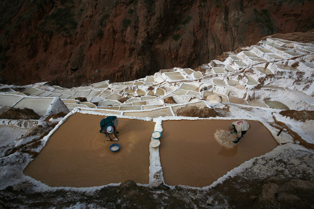 Dos comuneros trabajando en las pozas de sal en Maras durante la etapa de recolección artesanal