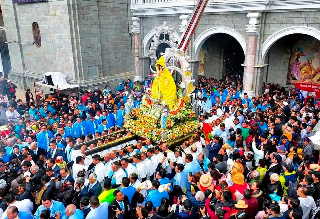 Procesión multitudinaria de la Virgen de la Puerta en Otuzco, con la imagen vestida de amarillo y rodeada por fieles y bandas musicales frente al templo principal