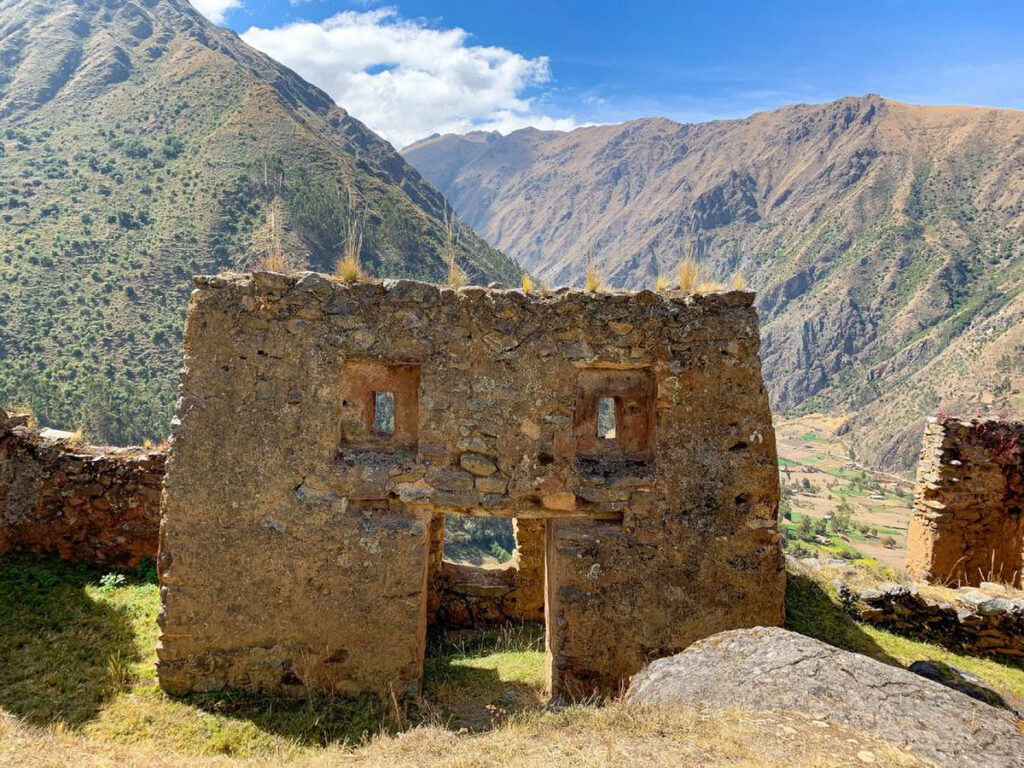 Muro de piedra con dos ventanas trapezoidales en Pumamarka, enmarcando el paisaje montañoso del Valle Sagrado