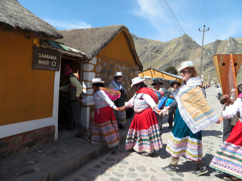 Visitantes bailando con pobladoras locales en una calle empedrada de Sibayo durante una actividad de turismo rural