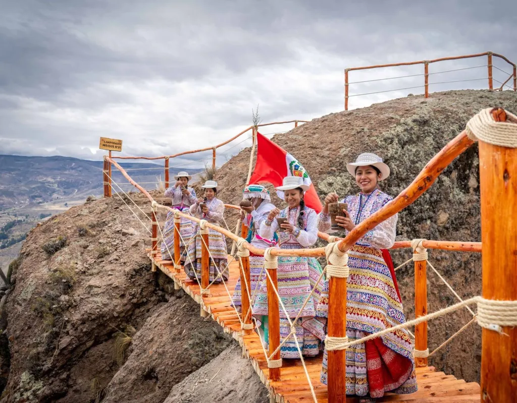 Mujeres peruanas con trajes típicos cruzando un puente colgante en las Fiestas Patrias