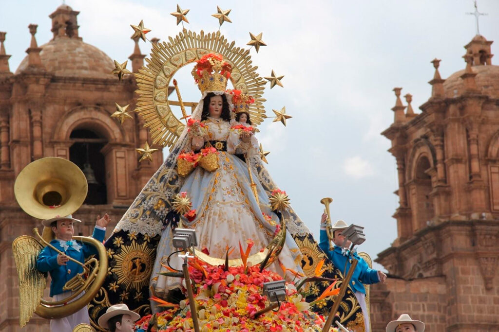 Procesión de la Virgen de la Candelaria en Puno, Perú, con la imagen decorada con flores y rodeada de músicos en uniforme tradicional frente a una iglesia colonial
