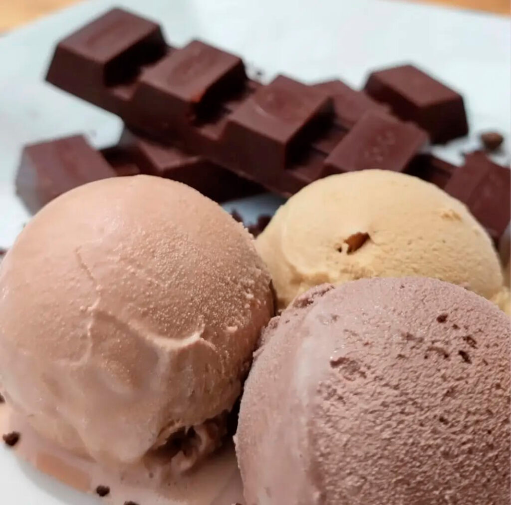 Tres bolas de gelato artesanal con trozos de chocolate en primer plano, servidas en una bandeja