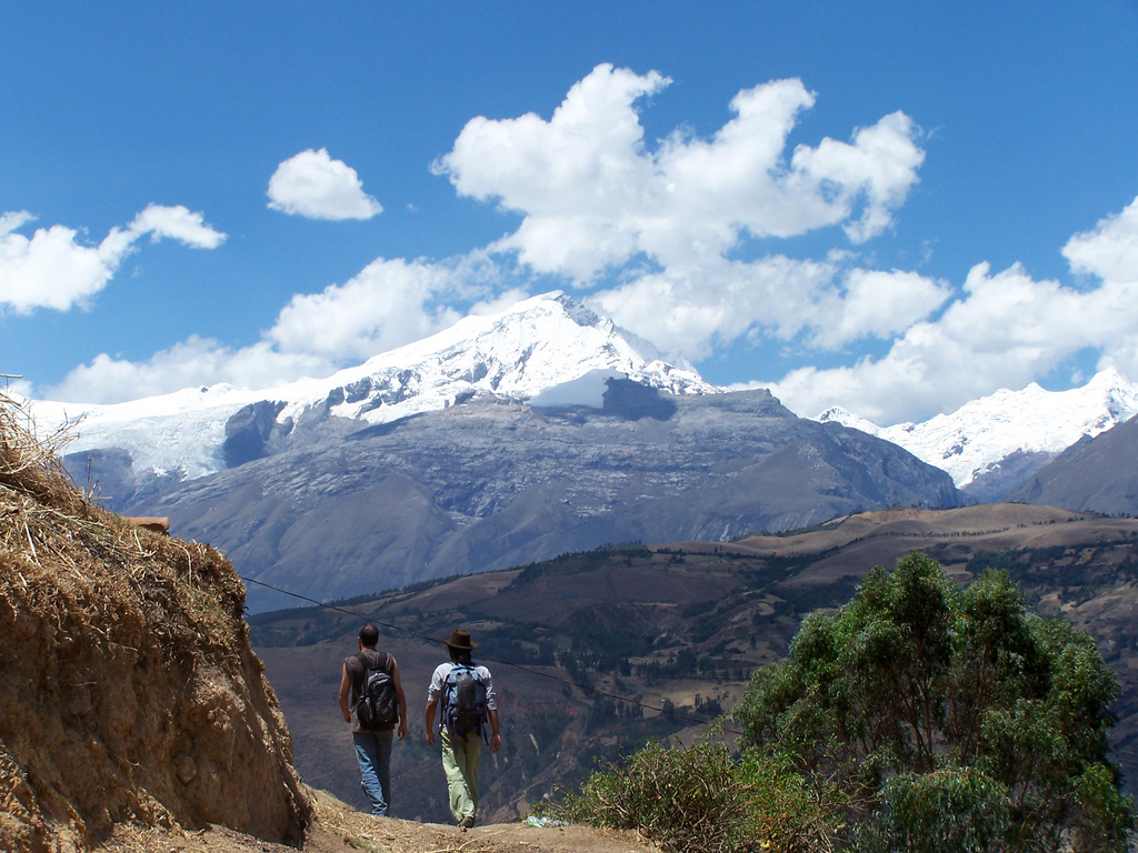 dos senderistas caminando con vista a montañas nevadas en la Cordillera Blanca