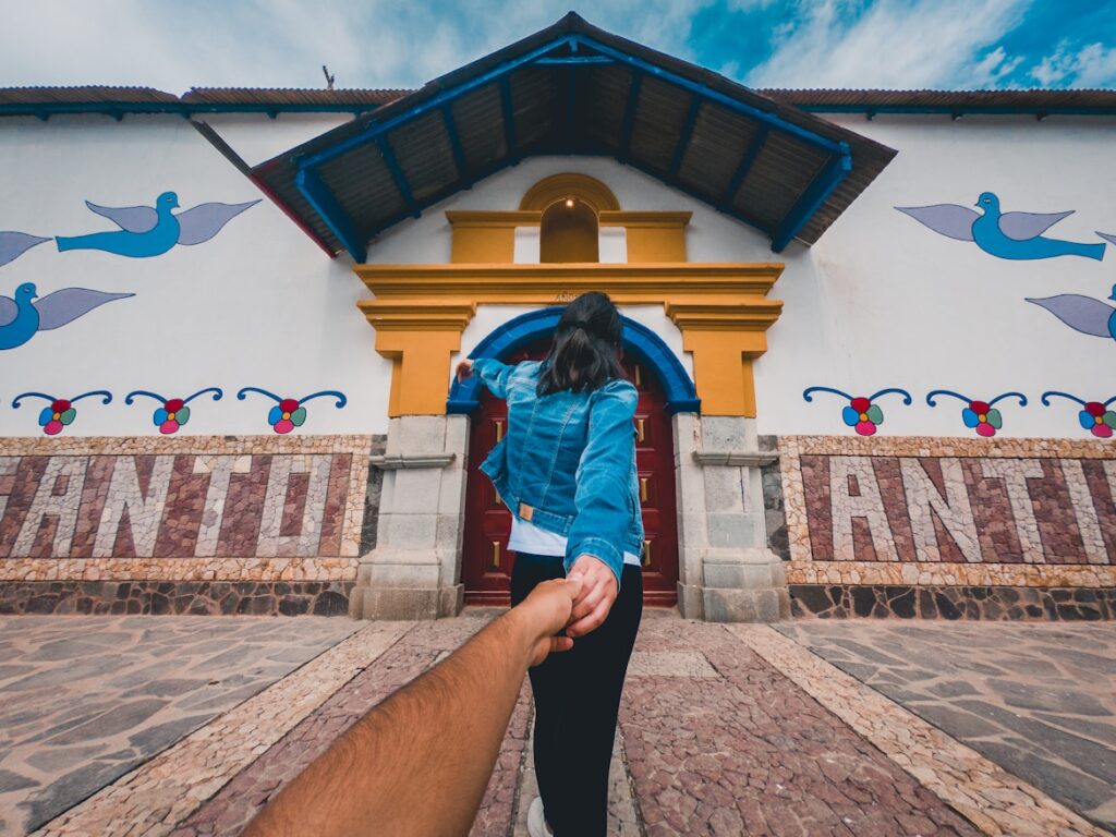 Pareja ingresando a una fachada decorada con arte naïf en Antioquía durante una visita de un día