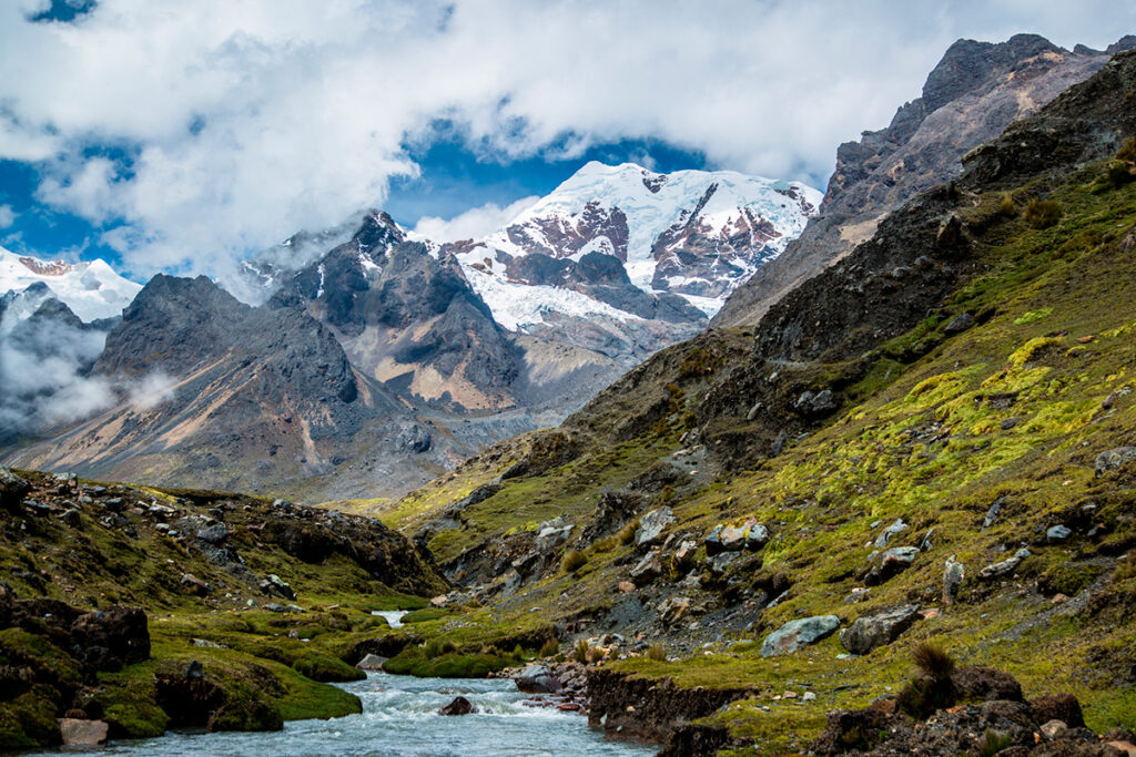 Paisaje del valle del Ausangate con un río de deshielo que recorre los pastos altoandinos bajo las cumbres nevadas del Cusco