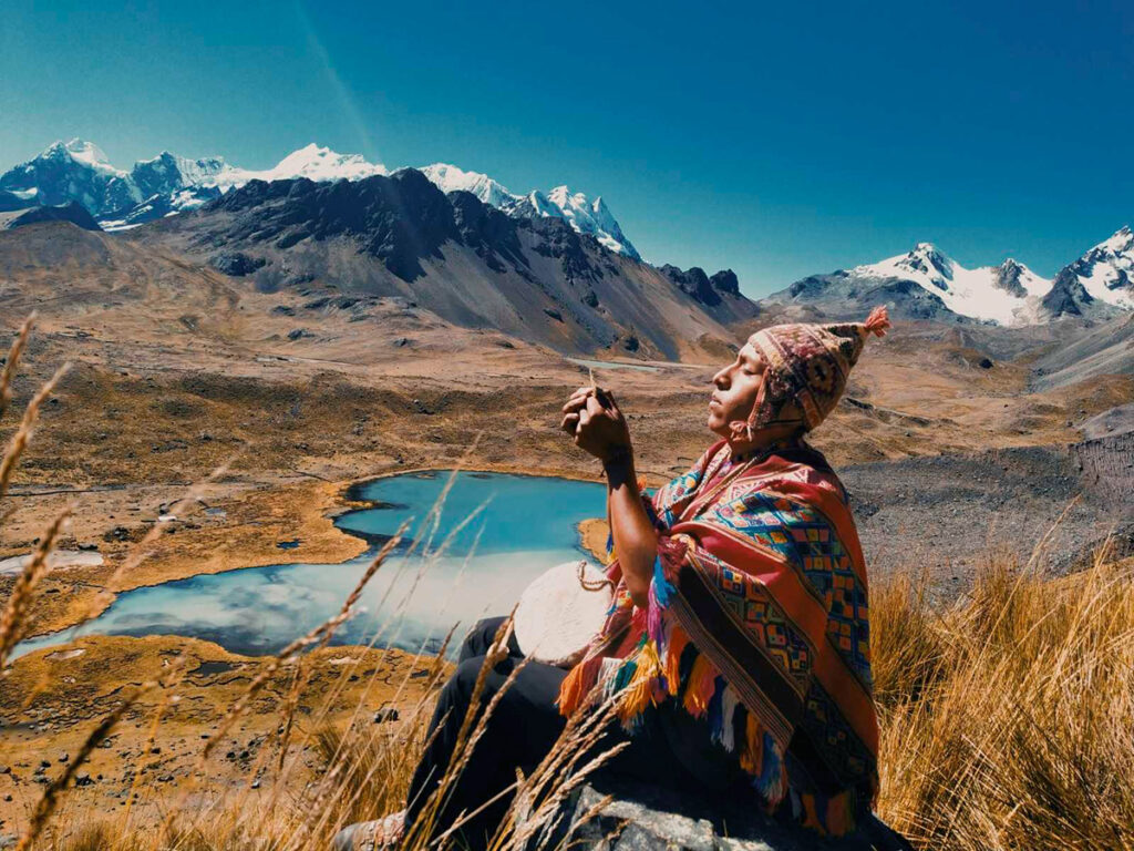 hombre de los andes realizando un ritual espiritual frente a una laguna en los Andes del Perú