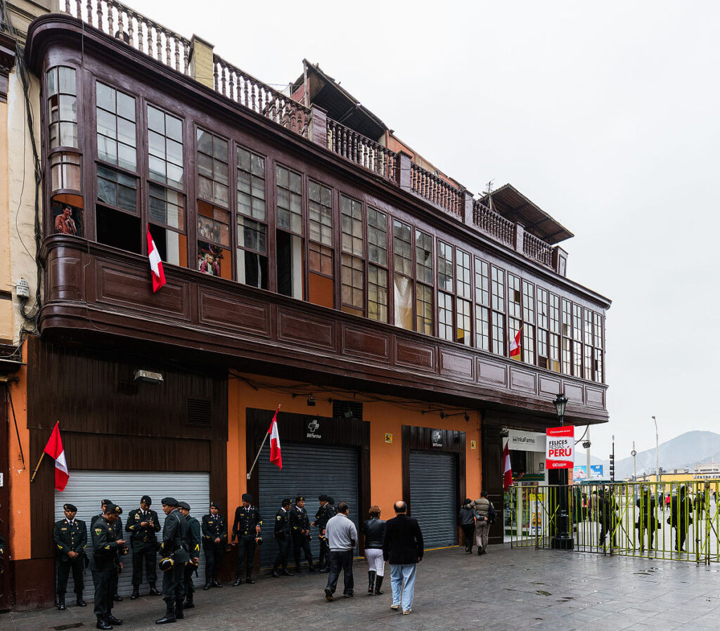 Fachada de la Casa Aliaga en el Centro Histórico de Lima, con balcones de madera y banderas del Perú