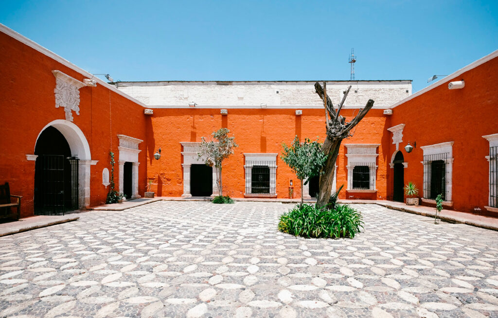 Patio principal de la Casa del Moral en Arequipa, con árbol de mora y muros de color naranja