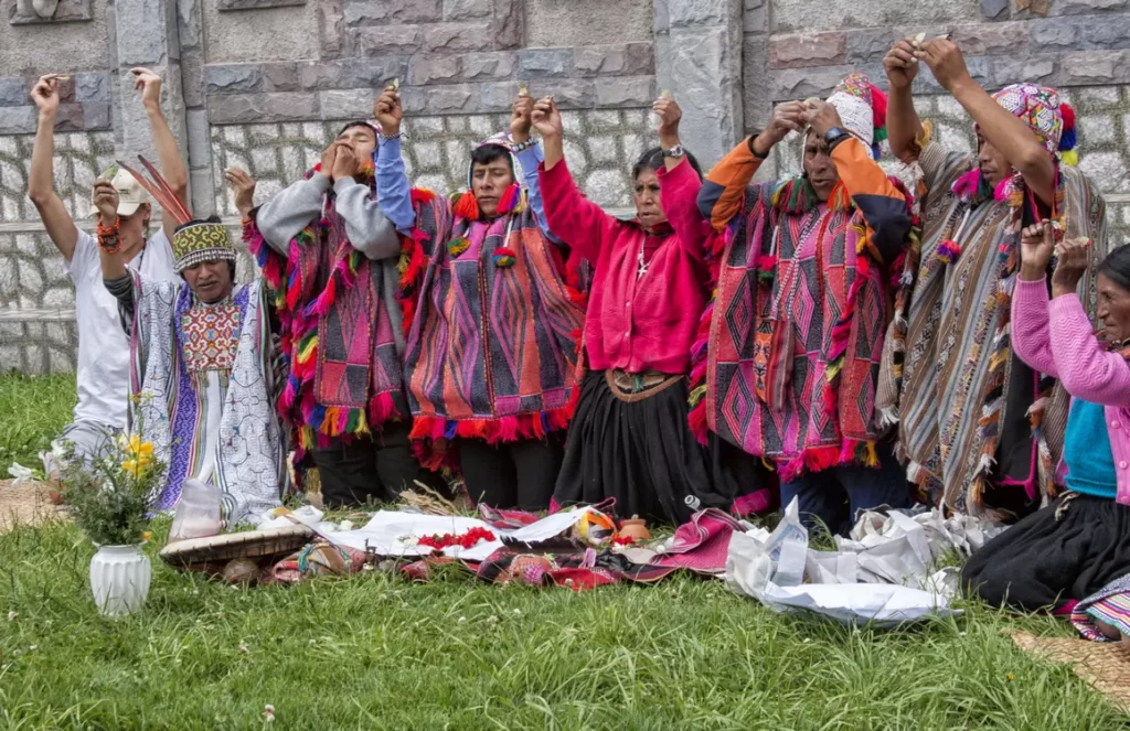 Ceremonia tradicional andina con participación comunitaria, realizada al aire libre frente a una pared de piedra