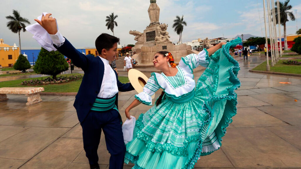 pareja bailando marinera en la Plaza Mayor de Trujillo con el Monumento a la Libertad de fondo