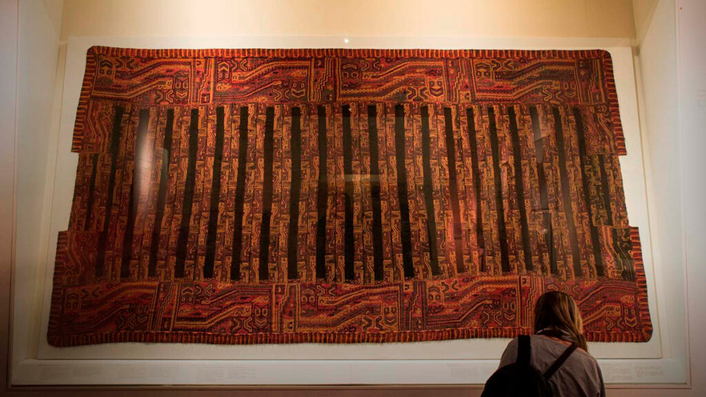 Manto textil Paracas expuesto en museo, ejemplo de la tradición textil prehispánica de la costa peruana