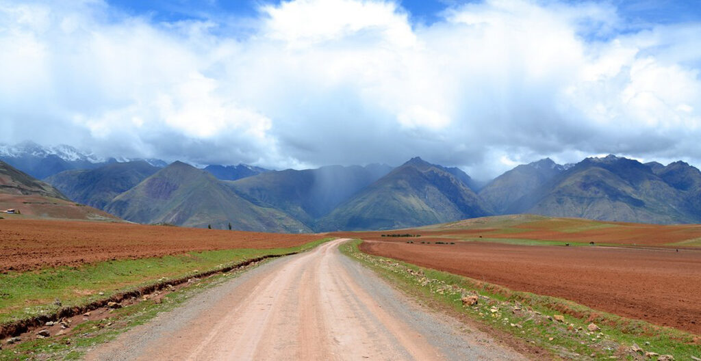 camino rural hacia Moray y Maras con montañas y nubes en el horizonte