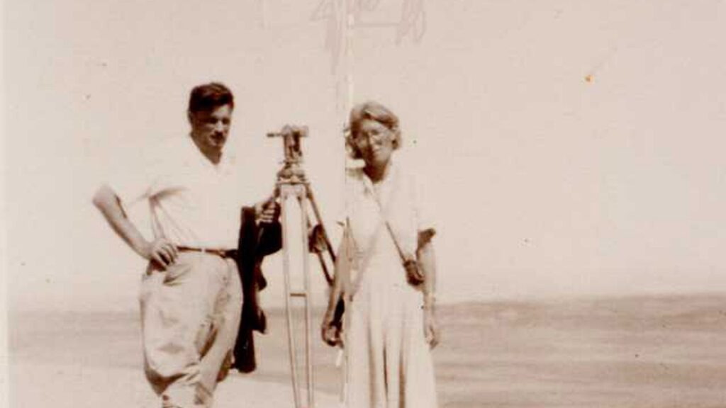 Fotografía en blanco y negro de Paul Kosok y María Reiche en el desierto de Nazca, con un teodolito entre ellos
