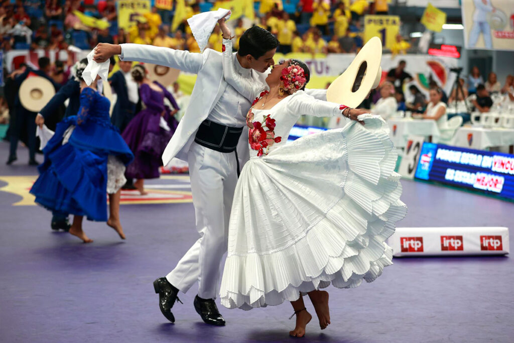 Pareja bailando marinera con pañuelos en un concurso, danza emblemática de la costa peruana