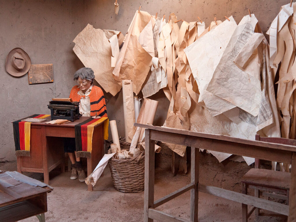 Interior del Museo María Reiche con una figura que representa a María Reiche trabajando en su escritorio, rodeada de planos y dibujos colgados en la pared
