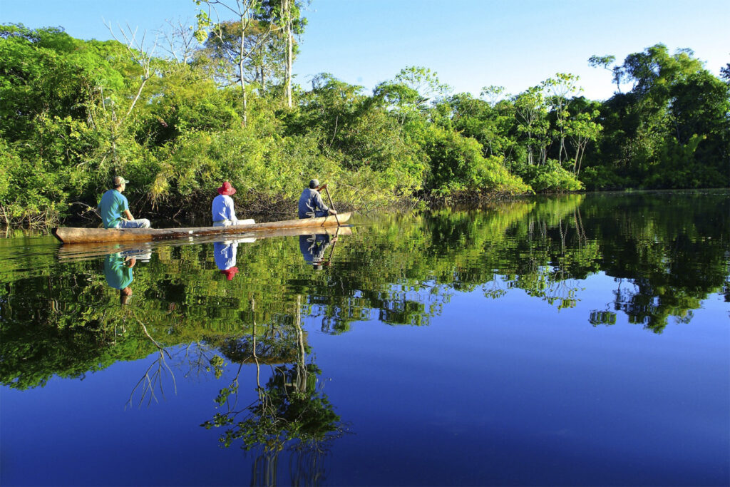 Turistas en canoa navegando entre los reflejos de la Reserva Nacional Pacaya Samiria