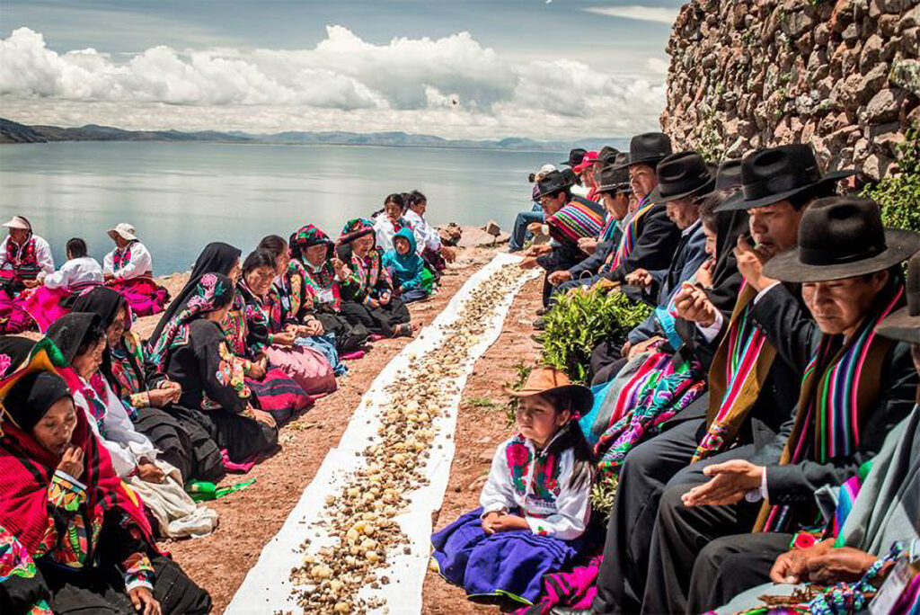 Comuneros reunidos durante el ritual anual de Pachamama y Pachata en Amantaní, con ofrendas alineadas sobre una manta ceremonial